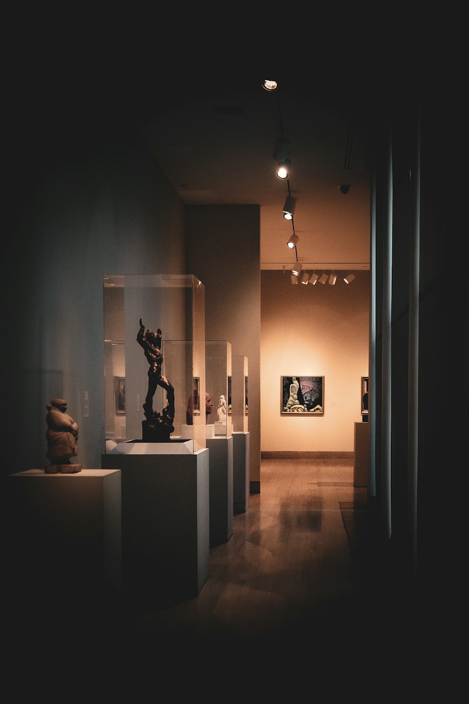 Corridoio di una galleria d'arte con sculture e un quadro.